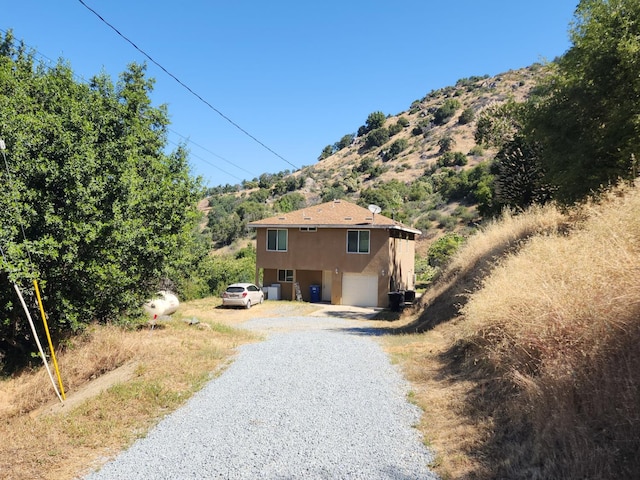 45704 Butternut Ln, Yokuts Valley, CA 93675 - view of property exterior with gravel driveway, stucco siding, a mountain view, and a garage