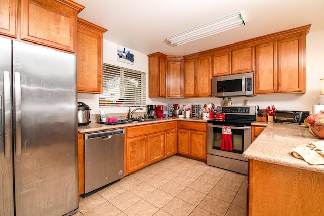 45704 Butternut Ln, Yokuts Valley, CA 93675 - kitchen featuring appliances with stainless steel finishes, brown cabinets, light tile patterned flooring, a sink, and light stone countertops