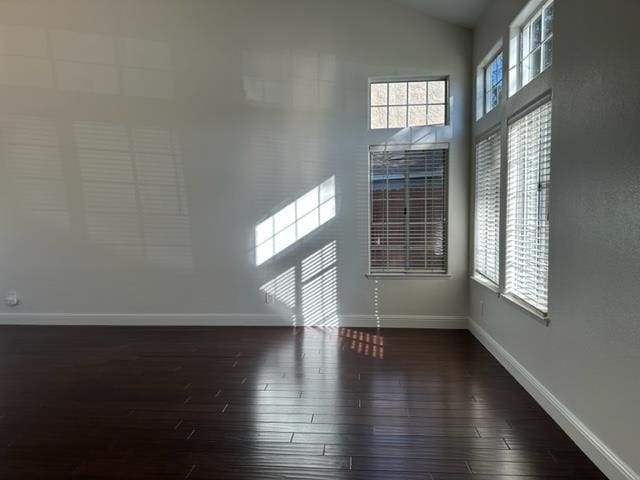 10752 N Windham Bay Cir, Fresno, CA 93730 - unfurnished living room featuring baseboards, dark wood-type flooring, and vaulted ceiling