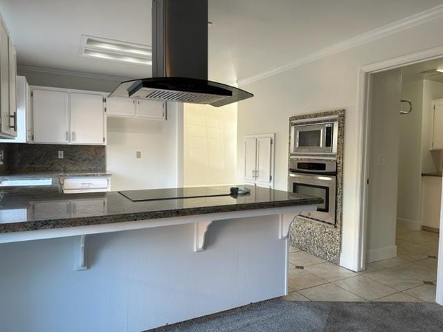 10752 N Windham Bay Cir, Fresno, CA 93730 - kitchen featuring island range hood, appliances with stainless steel finishes, dark stone counters, ornamental molding, and white cabinets