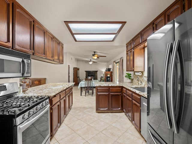 12502 Rd 37 Unit 1/2, Madera, CA 93636 - kitchen with appliances with stainless steel finishes, a peninsula, a ceiling fan, light stone countertops, and light tile patterned floors
