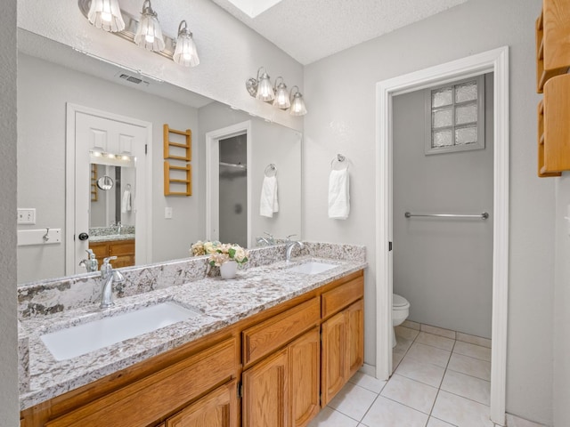 12502 Rd 37 Unit 1/2, Madera, CA 93636 - bathroom featuring toilet, tile patterned flooring, a skylight, double vanity, and a textured ceiling