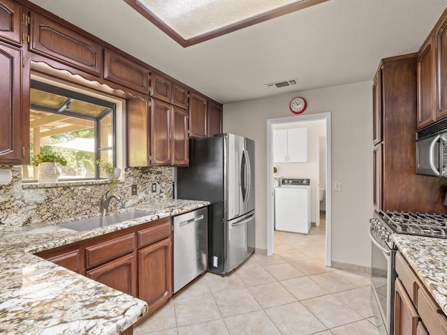 12502 Rd 37 Unit 1/2, Madera, CA 93636 - kitchen with stainless steel appliances, washer / dryer, tasteful backsplash, a sink, and light tile patterned floors