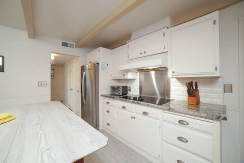 5543 N 7th St, Fresno, CA 93710 - kitchen with under cabinet range hood, black electric cooktop, freestanding refrigerator, beamed ceiling, and backsplash