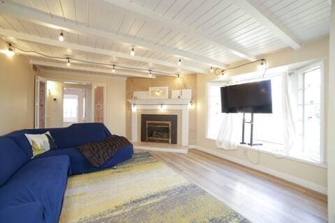 5543 N 7th St, Fresno, CA 93710 - living area with wood finished floors, wooden ceiling with exposed beams, baseboards, and a fireplace with raised hearth