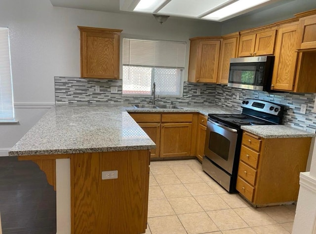 5323 W Garland Ave, Fresno, CA 93722 - kitchen with stainless steel appliances, a sink, a peninsula, backsplash, and brown cabinetry