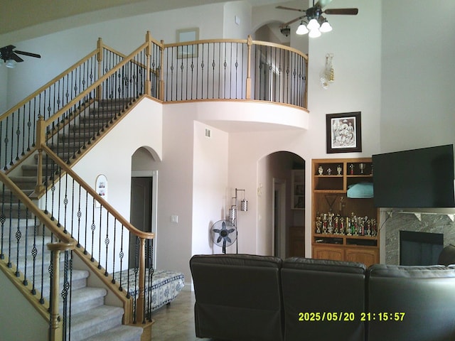 3030 Golf Dr W, Chowchilla, CA 93610 - living room featuring a ceiling fan, arched walkways, stairway, a towering ceiling, and a high end fireplace
