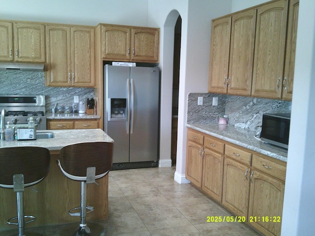 3030 Golf Dr W, Chowchilla, CA 93610 - kitchen featuring appliances with stainless steel finishes, extractor fan, backsplash, arched walkways, and a breakfast bar area