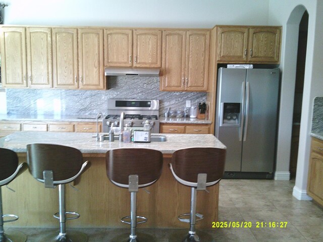 3030 Golf Dr W, Chowchilla, CA 93610 - kitchen featuring stainless steel fridge, under cabinet range hood, gas range oven, decorative backsplash, and a sink