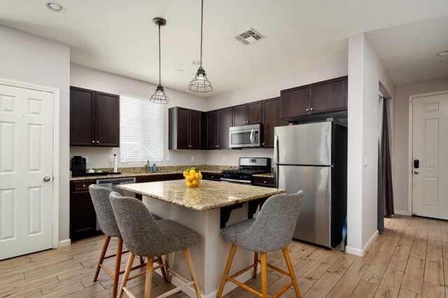 2326 W Flagstaff, Visalia, CA 93291 - kitchen with appliances with stainless steel finishes, a breakfast bar area, dark brown cabinets, light wood-style floors, and recessed lighting