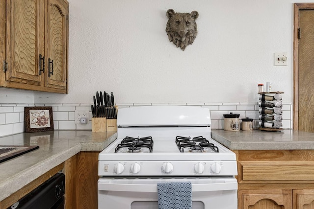 56981 Sequoia Dr, Springville, CA 93265 - kitchen featuring white gas range, backsplash, brown cabinetry, and light countertops