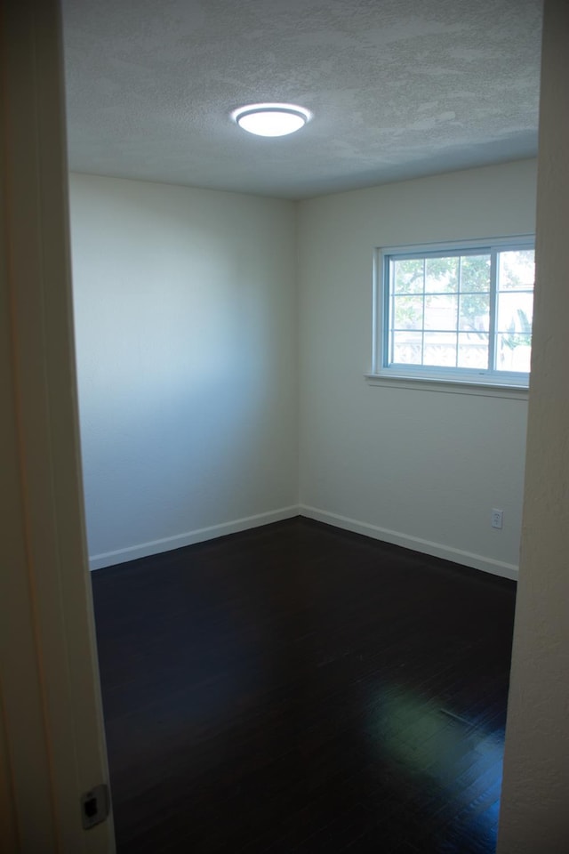 1913 N Waukena Way, Hanford, CA 93230 - spare room featuring a textured ceiling, dark wood-style floors, and baseboards
