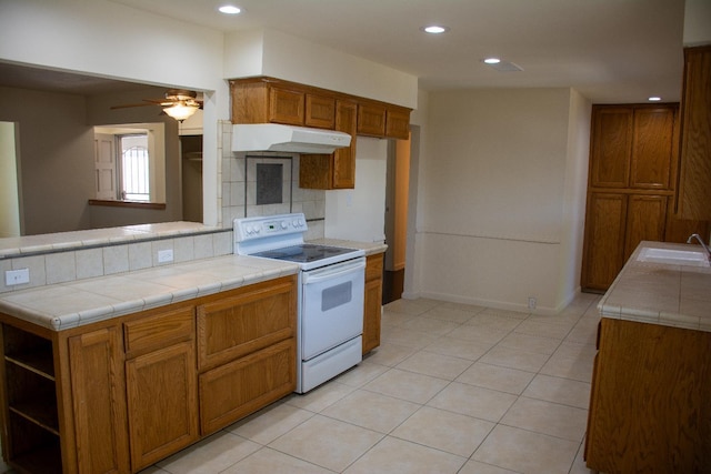 1913 N Waukena Way, Hanford, CA 93230 - kitchen with white electric range oven, under cabinet range hood, tasteful backsplash, brown cabinetry, and recessed lighting