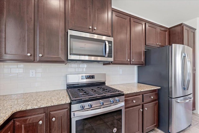 1799 Bolton Ave, Tulare, CA 93274 - kitchen featuring appliances with stainless steel finishes, dark brown cabinets, decorative backsplash, and light stone countertops