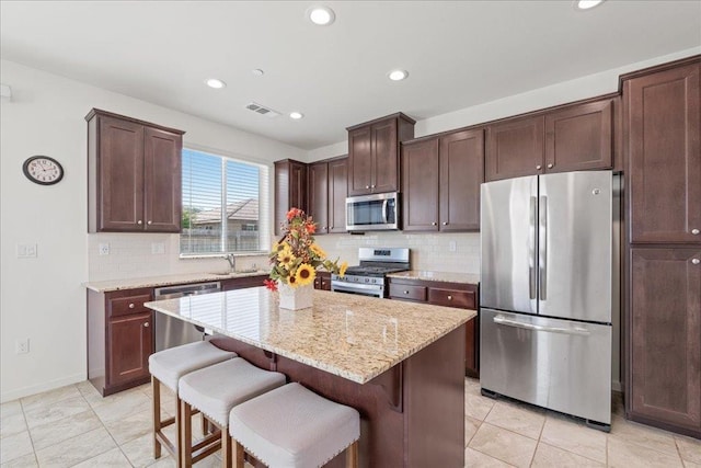 1799 Bolton Ave, Tulare, CA 93274 - kitchen with stainless steel appliances, a sink, tasteful backsplash, light stone countertops, and a kitchen bar