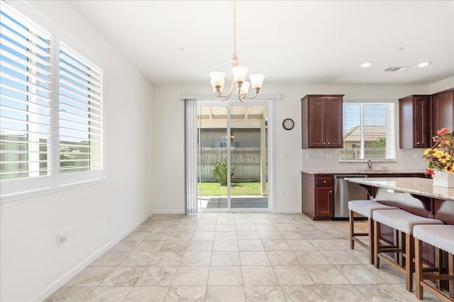 1799 Bolton Ave, Tulare, CA 93274 - kitchen featuring dishwasher, a chandelier, a kitchen breakfast bar, backsplash, and pendant lighting