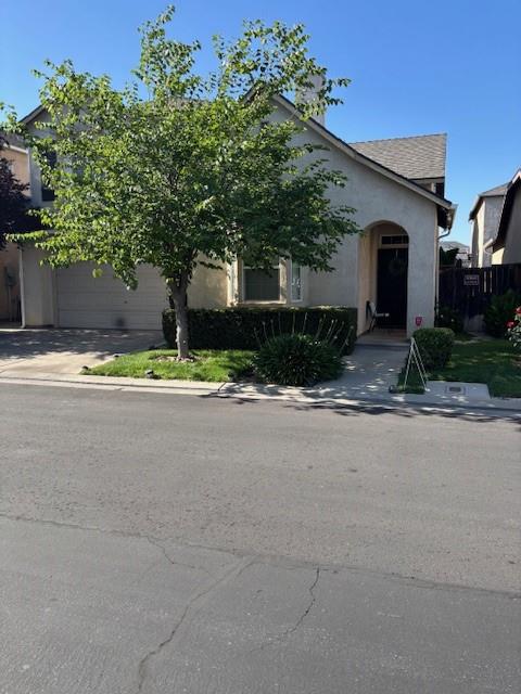 783 W Bordeaux Ln, Clovis, CA 93619 - view of property hidden behind natural elements with stucco siding, driveway, and a garage