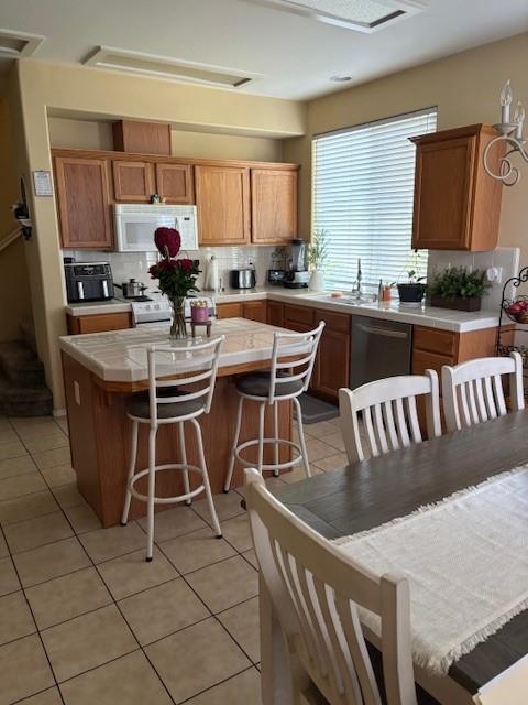 783 W Bordeaux Ln, Clovis, CA 93619 - kitchen with white microwave, stainless steel dishwasher, a sink, tasteful backsplash, and light tile patterned flooring