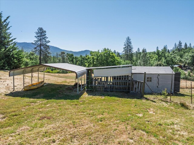 34133 Keller Rd, North Fork, CA 93643 - rear view of property featuring a lawn, a detached carport, a mountain view, and an outbuilding