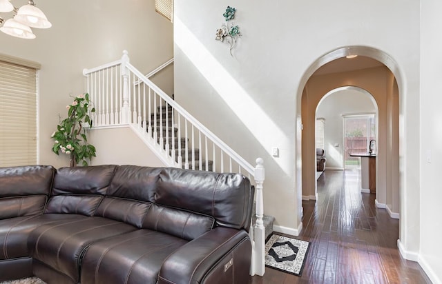 7026 E Dayton Ave, Fresno, CA 93737 - living area featuring dark wood-style flooring, arched walkways, baseboards, a high ceiling, and stairs