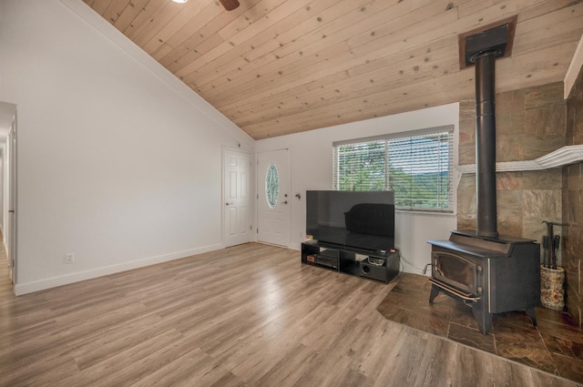 44719 Savage Rd, Coarsegold, CA 93614 - living area featuring a wood stove, vaulted ceiling, wood ceiling, wood finished floors, and baseboards
