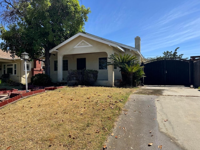 1382 N Thorne Ave, Fresno, CA 93728 - view of front of home with concrete driveway, stucco siding, a gate, a front lawn, and a chimney