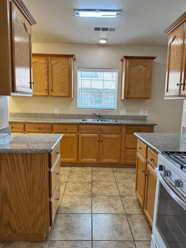 1382 N Thorne Ave, Fresno, CA 93728 - kitchen featuring a sink, stone countertops, light tile patterned flooring, gas range oven, and brown cabinets