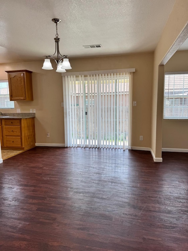 1382 N Thorne Ave, Fresno, CA 93728 - unfurnished dining area with plenty of natural light, dark wood-style flooring, baseboards, and a textured ceiling
