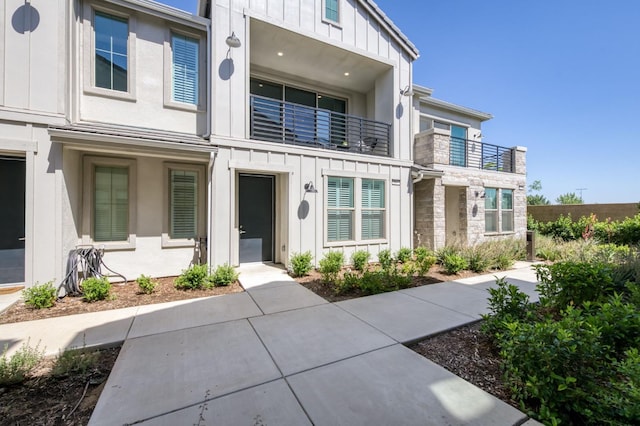 2867 E Tamarind Dr, Fresno, CA 93730 - view of front of home featuring board and batten siding, stone siding, and a balcony
