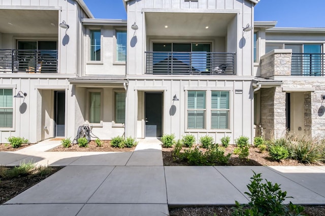 2867 E Tamarind Dr, Fresno, CA 93730 - view of property featuring board and batten siding, a balcony, and stone siding