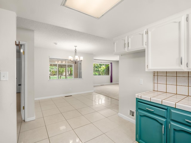 1646 W Millbrae Ave, Fresno, CA 93711 - kitchen with white cabinetry, baseboards, tasteful backsplash, and a chandelier