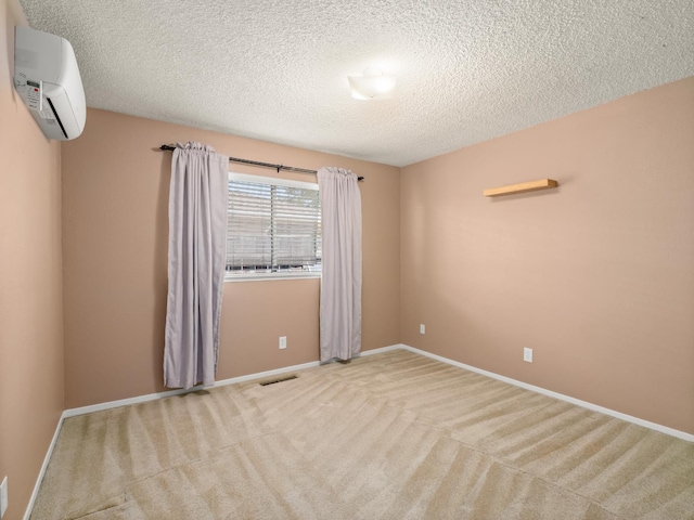 1646 W Millbrae Ave, Fresno, CA 93711 - unfurnished room featuring a wall unit AC, light colored carpet, a textured ceiling, and baseboards