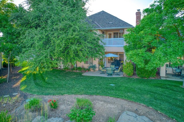 2895 W Kensington Ln, Fresno, CA 93711 - rear view of house featuring a balcony, a patio, a chimney, and a lawn