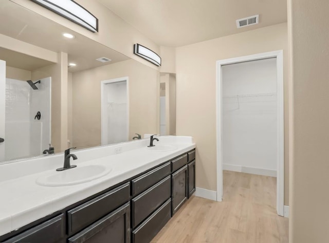 1656 N Cecelia Ave, Fresno, CA 93722 - full bathroom featuring double vanity, wood finished floors, a walk in closet, baseboards, and recessed lighting