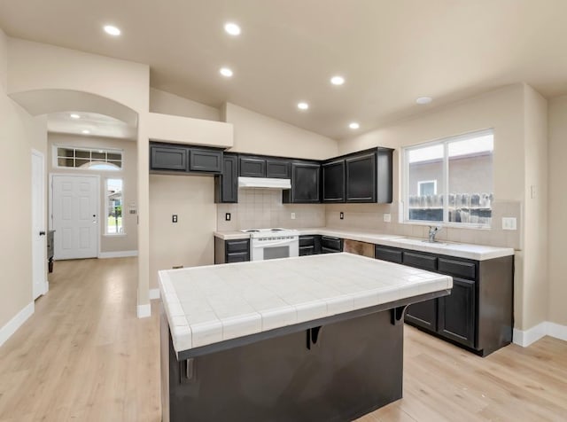 1656 N Cecelia Ave, Fresno, CA 93722 - kitchen featuring under cabinet range hood, tile countertops, tasteful backsplash, light wood-style floors, and recessed lighting