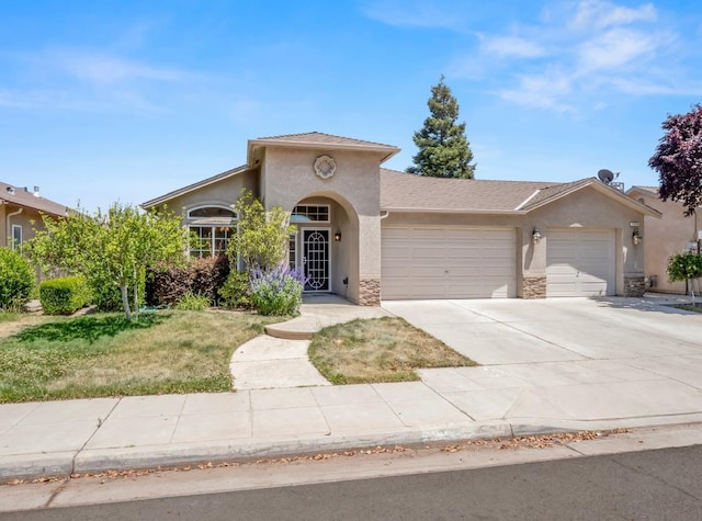 1656 N Cecelia Ave, Fresno, CA 93722 - mediterranean / spanish home featuring an attached garage, stucco siding, concrete driveway, and stone siding