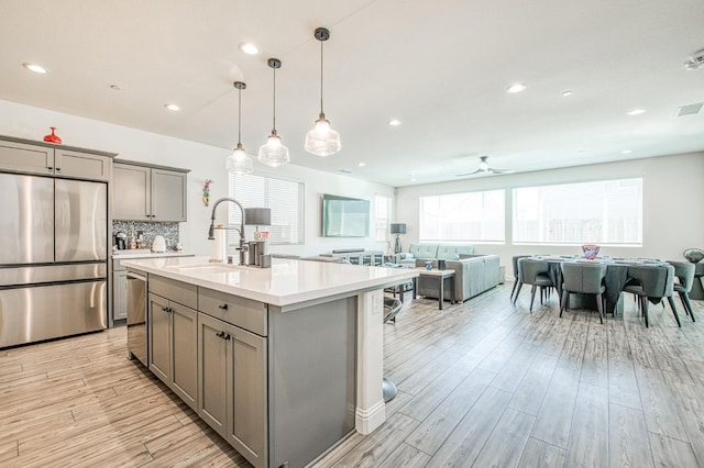 4148 Beverly Ave, Clovis, CA 93619 - kitchen with stainless steel appliances, gray cabinetry, a sink, light countertops, and light wood-style floors