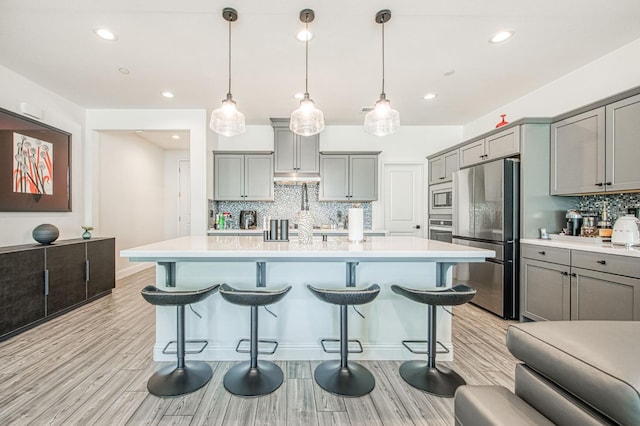 4148 Beverly Ave, Clovis, CA 93619 - kitchen featuring appliances with stainless steel finishes, gray cabinets, a kitchen breakfast bar, backsplash, and recessed lighting
