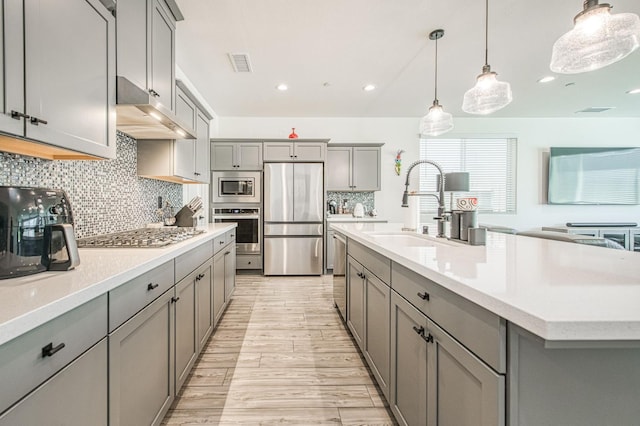4148 Beverly Ave, Clovis, CA 93619 - kitchen featuring appliances with stainless steel finishes, gray cabinetry, under cabinet range hood, a sink, and light countertops