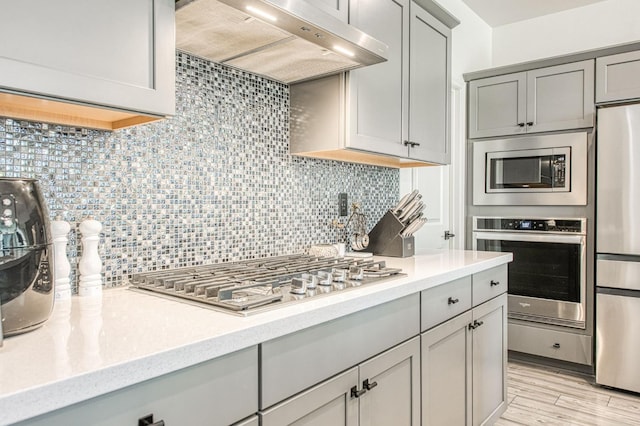 4148 Beverly Ave, Clovis, CA 93619 - kitchen featuring stainless steel appliances, gray cabinetry, under cabinet range hood, and decorative backsplash