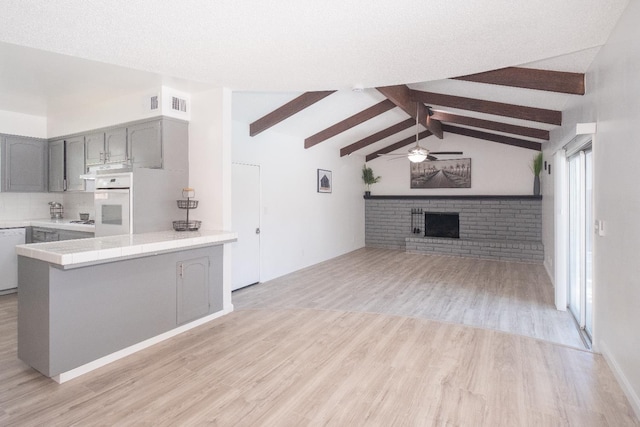1617 W Indianapolis Ave, Fresno, CA 93705 - kitchen featuring gray cabinetry, white appliances, a ceiling fan, a brick fireplace, and light wood finished floors