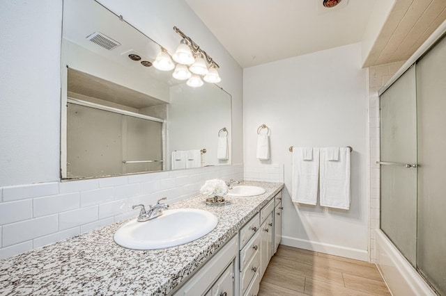 926 E Birch Ave, Fresno, CA 93720 - full bathroom featuring double vanity, backsplash, bath / shower combo with glass door, wood finished floors, and baseboards
