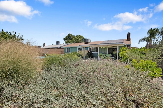 2141 Akers St, Visalia, CA 93277 - back of house featuring a chimney, roof mounted solar panels, and a sunroom