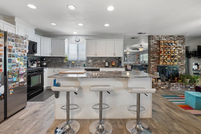 2141 Akers St, Visalia, CA 93277 - kitchen featuring black appliances, light wood-type flooring, white cabinets, tasteful backsplash, and a sink