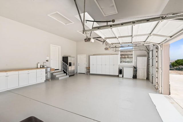 14215 Killarney Dr, Madera, CA 93636 - garage with stainless steel fridge with ice dispenser, washing machine and dryer, a garage door opener, and a sink