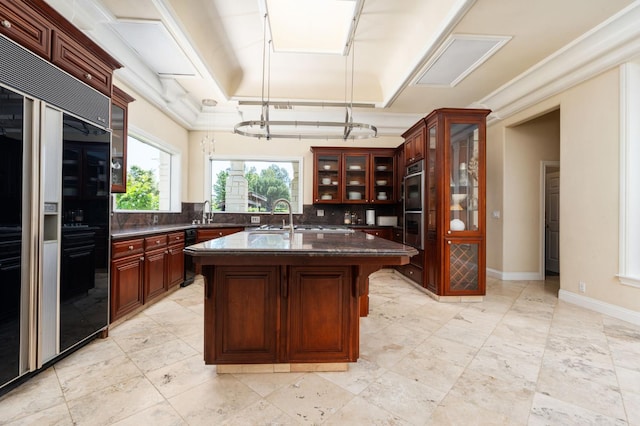 14215 Killarney Dr, Madera, CA 93636 - kitchen with built in refrigerator, decorative backsplash, a sink, a kitchen island with sink, and glass insert cabinets