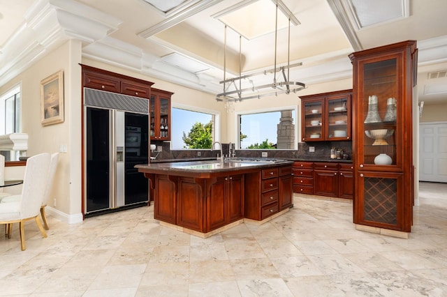 14215 Killarney Dr, Madera, CA 93636 - kitchen with built in fridge, reddish brown cabinets, dark countertops, backsplash, and an island with sink