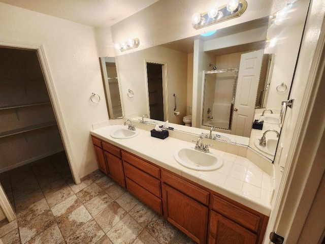 4686 W Sierra Ave, Fresno, CA 93722 - full bathroom featuring a shower stall, double vanity, a spacious closet, and toilet