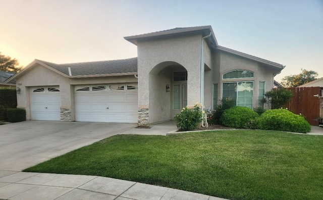4686 W Sierra Ave, Fresno, CA 93722 - view of front facade with stucco siding, a garage, driveway, and stone siding