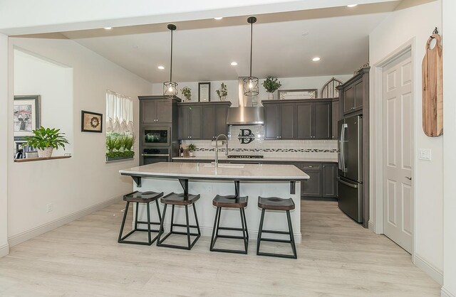 1523 N Ryan Ave, Clovis, CA 93619 - kitchen featuring appliances with stainless steel finishes, wall chimney range hood, a sink, decorative backsplash, and a kitchen breakfast bar
